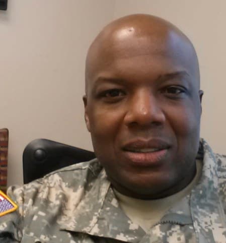 Our owner smiling in his Army uniform with an American flag patch