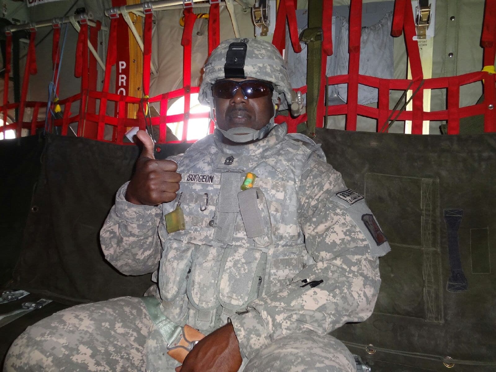 Our owner in full Army gear and helmet giving a thumbs up inside a military aircraft